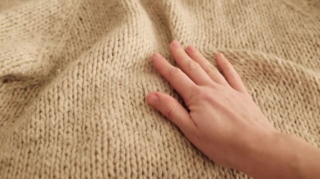 Closeup video of hands touching soft knitted wool fabric. Appreciating pleasant texture of high quality textile for clothes. Soft and cozy textile. Ivory winter knitted sweater. 