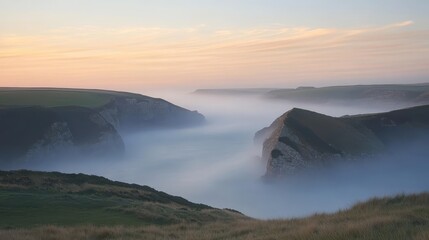 Rocky coastline shrouded in dense fog at sunrise with soft light illuminating the landscape