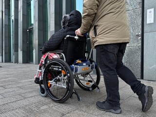 Obraz premium Caregiver Assisting Disabled Person in Wheelchair Outdoors