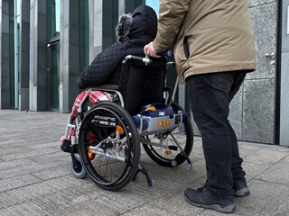 Obraz premium Caregiver Assisting Disabled Person in Wheelchair Outdoors