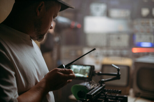 Director of photography with a camera in his hands on the set. Professional videographer at work on filming a movie, commercial or TV series. Filming process indoors, studio