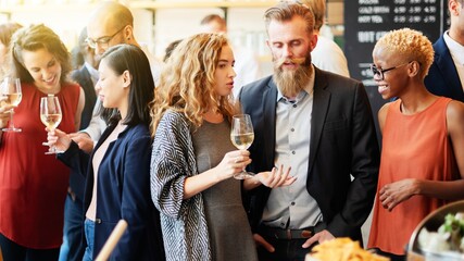 Group of diverse people socializing at a party, holding wine glasses. Men and women chatting,...