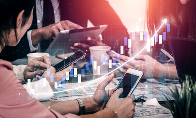 A dynamic business meeting scene showing multiple participants engaged with various digital devices, analyzing finance data visualization during discussion. Impute