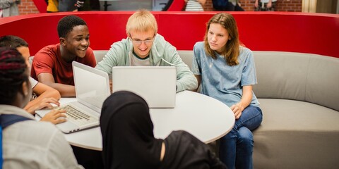 Diverse group of students studying together with laptops. Collaborative learning in a modern...