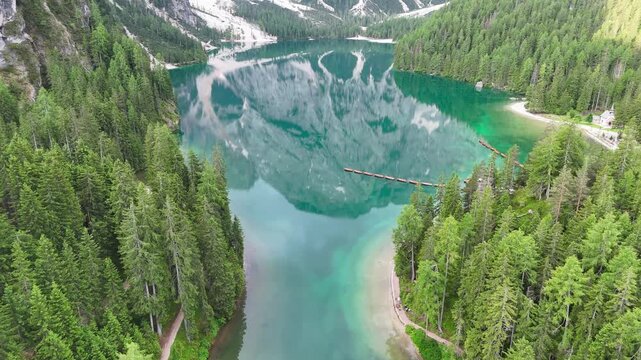 Vue a&eacute;rienne cin&eacute;matique du lac de Braies avec les reflets des montagnes des Dolomites et ses barques en bois