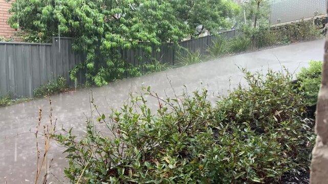 Torrential rain extreme thunderstorm weather event water splashing and pouring down an urban concrete driveway