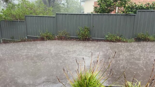 video with audio thunder lightning with torrential rain pouring down splashing drops and water rushing downhill on a concrete driveway