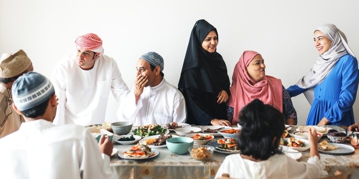 A dive group of Middle Eastern gather around a table filled with traditional dishes. The scene showcases unity and cultural richness among Arab families enjoying a meal together.