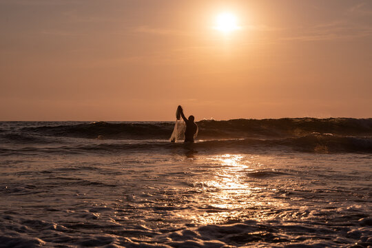 Fisherman throwing a cast net or atarraya at the seashore with water at his waist. Artisanal fishing with a throw net. costalegre
