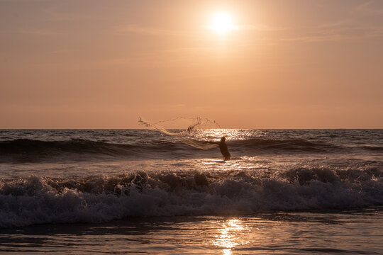 Fisherman throwing a cast net or atarraya at the seashore with water at his waist. Artisanal fishing with a throw net. costalegre