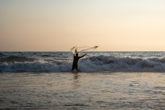 Fisherman throwing a cast net or atarraya at the seashore with water at his waist. Artisanal fishing with a throw net. costalegre