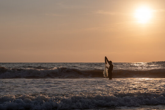 Fisherman throwing a cast net or atarraya at the seashore with water at his waist. Artisanal fishing with a throw net. costalegre