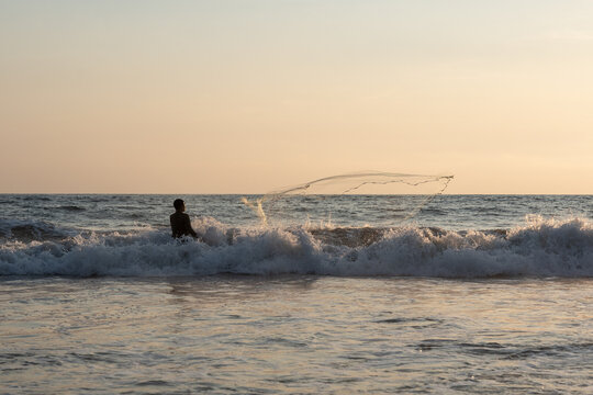 Fisherman throwing a cast net or atarraya at the seashore with water at his waist. Artisanal fishing with a throw net. costalegre
