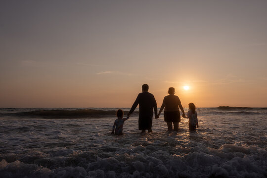 Silhouette of a family enjoying the sunset on the beach. Family tourism beach. Costa Grande, costalegre.