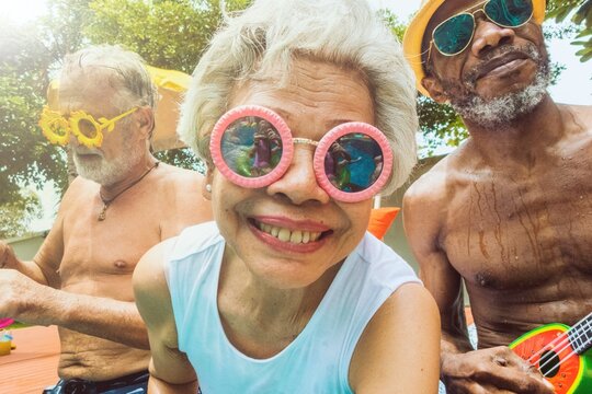 Closeup of diverse senior adults sitting by the pool enjoying summer together