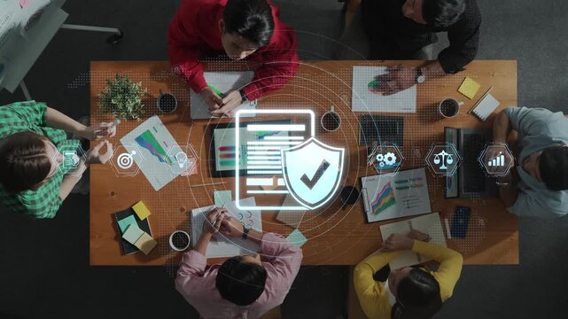 A diverse business team gathers around a table to discuss data protection strategies, featuring digital security icons and colorful charts in a modern office setting. Raster