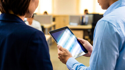 Professional colleagues analyzing digital business data on tablet in bright corporate office