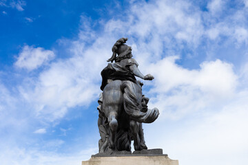 Statue of a figure on horseback with a group of smaller figures in a public square under a blue sky