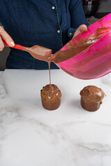 A pastry chef covering small panettone cakes with melted chocolate_vertical.