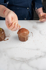 A pastry chef placing crunchy caramel on top of the small panettone cakes.