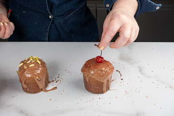 A pastry chef placing a fresh cherry on top of the small panettone.