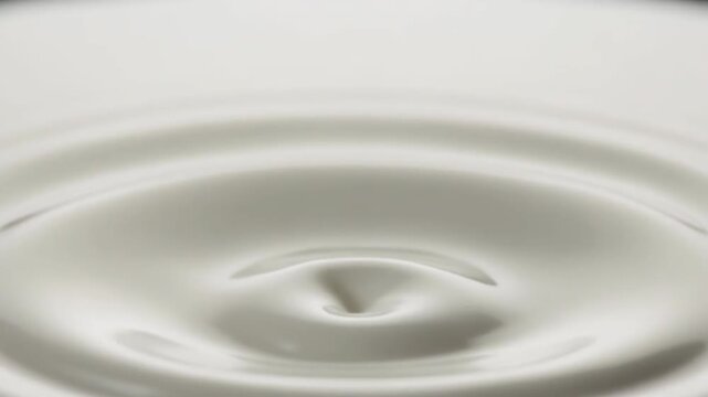 Closeup slow motion of milk splashing and creating ripples. 4k Food Footage Video