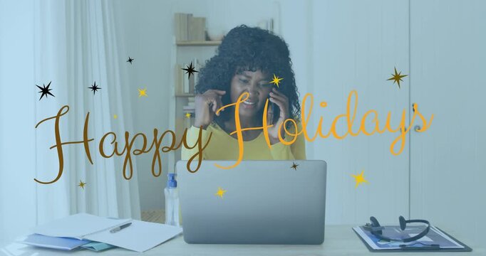 Woman at desk getting phone call sharing holiday chat as Happy Holidays stars animating over laptop