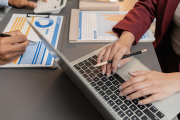 A business meeting scene where professionals review financial charts and exchange insights,...
