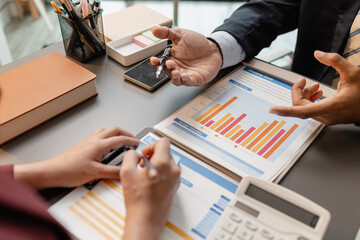 Business professionals meeting at a modern office table, reviewing charts and budget reports while...