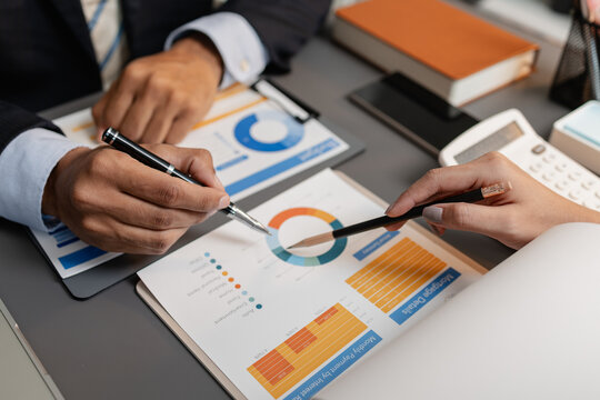 A business meeting scene where professionals review financial charts and exchange insights, highlighting strategic planning and collaborative decision making in a modern office environment. - Powered by Adobe