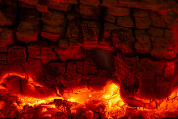 Close-up of glowing embers and burning charcoal with intense red and orange light. Abstract fire texture illustrating heat, energy, combustion, and powerful thermal processes