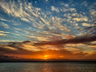Naklejka premium Dramatic sunset over calm ocean with colorful sky and clouds