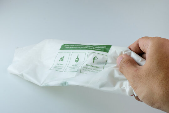 Hand holding eco friendly biodegradable plastic bag with sustainability labels. Perfect for sustainability campaigns, eco education, green business content, waste reduction, and green lifestyle