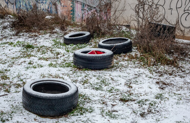 Abandoned car tires dumped in an urban wasteland during winter, illustrating environmental pollution, illegal dumping, and ecological damage in neglected city areas