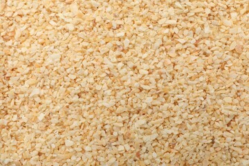 Granulated dried garlic as background, top view