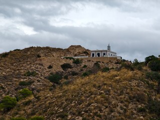 Fototapeta premium hilltop chapel silhouette, remote chapel above arid slopes, whitewashed chapel atop dry hillside
