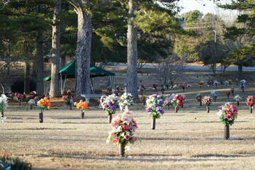 Obraz premium Scenic view of cemetery graves with vibrant flower arrangements and trees for memorial landscape and peace concepts