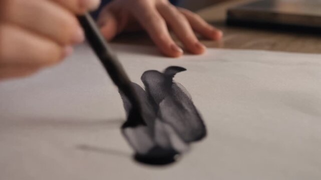 Hand holding calligraphy brush writing on paper.