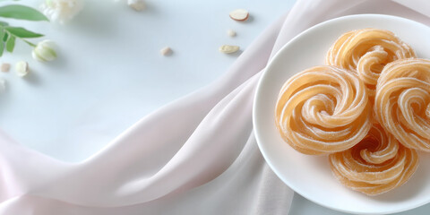 Sweet spiral shaped dessert on white plate with soft fabric and flower petals