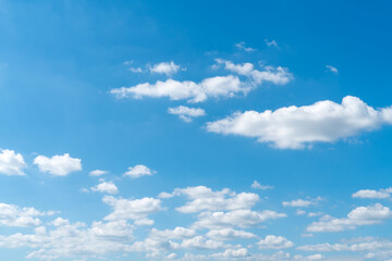 Obraz premium Wide shot of a bright blue sky with white fluffy cumulus clouds scattered throughout. Natural daylight background for weather, nature, or environmental concepts. High resolution and clear.