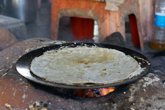 Traditional jowar roti cooks on a hot pan over intense heat, capturing the rustic essence of Maharashtrian cuisine, often paired with pitla, highlighting authentic village-style cooking and millets