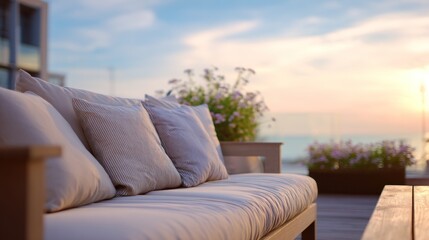 Naklejka premium Comfy outdoor couch overlooks a soft, pastel sunset with flowers on a wooden deck