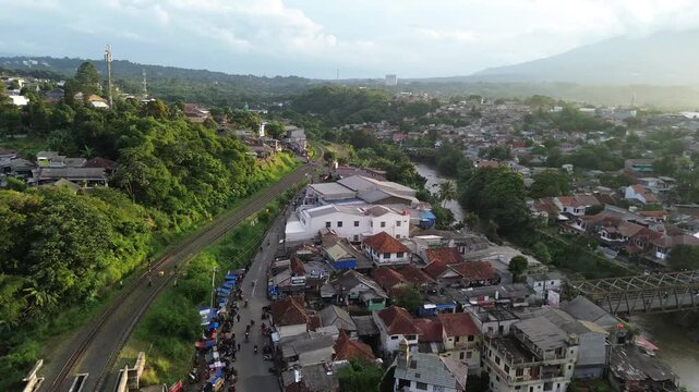 Aerial Drone View of Riverside Urban Neighborhood with Railway and Green Hills at Daylight