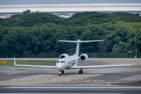 Jakarta, Indonesia - December 25, 2025: A private Gulfstream G550 business jet performs a turn on the taxiway at Soekarno-Hatta International Airport against a backdrop of dense green trees