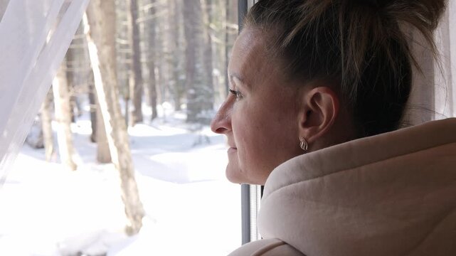 Mindful pause by window overlooking snowy forest woman finds emotional balance inspired by winter nature Quiet reflection during winter calm supports inner peace self care shaped by winter silence