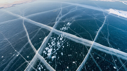 Frozen lake surface with cracked ice and snow from an aerial view