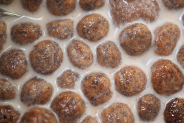 Brown round snacks in white liquid on a surface