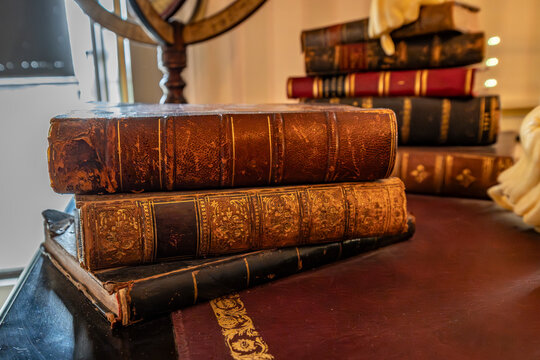 Stack of vintage leather bound books on an antique wooden desk