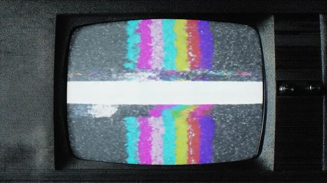 Vintage CRT television screen displaying static noise and glitchy color bar test pattern