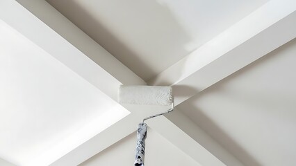 A person uses a paint roller to apply fresh white paint onto a geometrically patterned white ceiling, ensuring even coverage and a crisp finish.